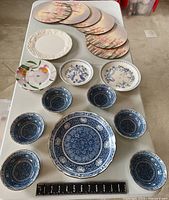 Top view of assorted plates and bowls on table including blue and white dinnerware and floral pieces.