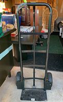 Front view of black metal hand truck dolly about 52 inches tall, showing handle and platform.