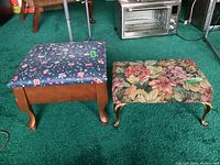 Two footstools side by side on green carpet, showing different floral upholstery and leg styles