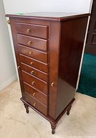 Front right angled view of wooden jewelry armoire showing drawers and top
