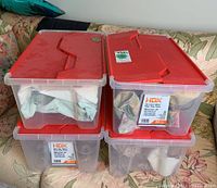 Four plastic storage totes with red lids containing wrapped glass stemware for safe storage and transport