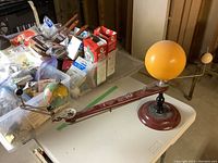 Full orrery assembly on table with orange sun sphere on one end and earth globe with moon on the other