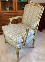 Side angled view showing the chair's wood frame, carved floral detail, and patterned striped upholstery fabric.