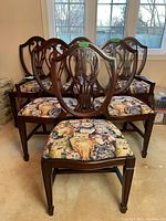 Six matching vintage wooden dining chairs with plush cat tapestry fabric seats. Two captain chairs with arms and four armless chairs are grouped together on carpet.