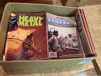 Box top-down view showing Heavy Metal magazine (March 1978) and National Lampoon magazine on top of stacked publications