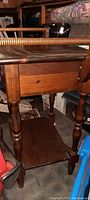 Side view of the antique vanity/nightstand showing the turned leg and the pull-out drawer.