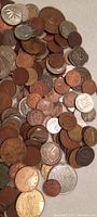 Pile of assorted vintage foreign coins showing a diverse variety of metals and designs.