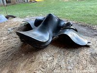 Left side view of black leather saddle showing pommel, cantle and overall wear