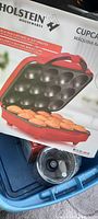 Box of red and black Holstein cupcake maker showing non-stick baking molds with silicone baking cups inside, labeled with specifications and product features.