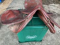 Overall top view of brown leather English saddle showing seat and flaps with wear and creases.