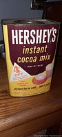 Front view of vintage Hershey's Instant Cocoa Mix 1-pound tin, showing branding, 4¢ off coupon, and color scheme.