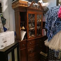 Full view of wooden hutch with glass doors and ornate carved top, showing side shelves and drawers at the bottom