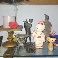 Photo of various small statuettes including candle holder and figurines on a glass shelf