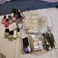 Overview of nail polish bottles, false nails in trays, nail glue, and applicators spread out on cloth surface