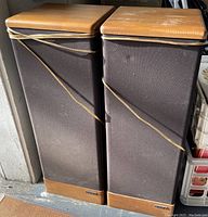 Pair of tall Advent Prodigy Tower speakers with brown fabric grills and wood finish on top and bottom, placed side by side.