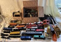 Wide view showing locomotives, train cars, and various track pieces with some accessory buildings in background
