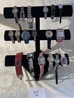 Photo showing 15 assorted wristwatches on a black velvet display stand (not included in sale) arranged in three rows.
