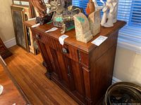 Full view of the wood Drexel cabinet showing three doors, one drawer, and various objects on top.