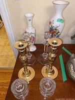 Overview of two brass candleholders and two hand-painted ceramic vases in background placed on wood table.