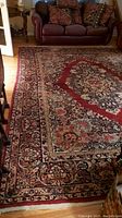 Overall view of the rug showing central medallion and surrounding border on hardwood floor