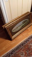 Framed oval landscape paintings stacked showing ornate gold frames with wear