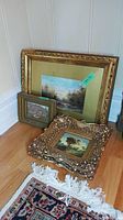 Group view: large gold ornate frame, small brown frame, one ornate gold frame on floor