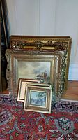 Group of multiple framed prints stacked against wall on rug
