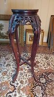 Front view of the wood plant stand showing curved legs, marble-look inlay top, and overall height.