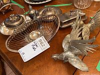 Wide view on wooden table showing salt and pepper shakers, silver colander style bowl, butter dishes, roosters figurines.
