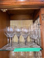 Shelf displaying 6 crystal wine glasses and 5 champagne flutes with cut detailing on stems