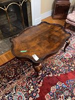 Full view of the wooden accent table showing its scalloped tabletop and curved cabriole legs.