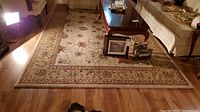 Full view of carpet placed on wood floor beneath living room furniture, showing overall condition and pattern.