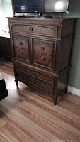 Frontal view of dresser showing five drawers, wood finish, metal ring pulls