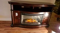 Full front view of cherry finish console with curved glass electric firebox and side cabinets