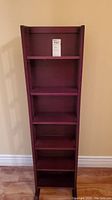 Front view of the tall wooden folding bookcase showing five shelves and a dark wood finish.