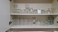 Two shelves of various clear glassware including drinking glasses and small custard bowls