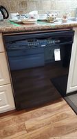 Black Kenmore dishwasher installed under kitchen counter, closed door showing front control panel.