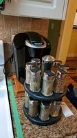 Keurig coffee maker and rotating spice rack with spice jars on kitchen counter.