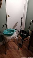 Photo showing commode with teal basin on top and walker in background