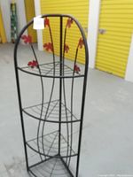 Full view of a four-tier metal corner shelving unit with rounded arch top. Shows black metal construction and wire shelves. Bottom shelf needs repair.