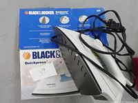 Black & Decker Quickpress electric iron with power cord and original packaging/manual in background