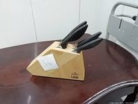 Knife block viewed from angle showing three knives inserted and label with number 56 on it.