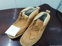 Top and side view of a pair of tan leather Timberland boots with padded ankle collars, showing the laces and overall used condition.