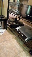 Full view of Lotus style rack shelf containing the Instant Pot on top shelf, electric wok with glass lid on middle shelf, and Lean Mean Fat Reducing Grilling Machine on bottom shelf.