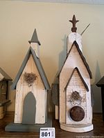 Front view of two wooden birdhouses painted in white with decorative details