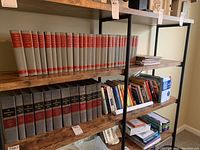 Photo showing upper bookshelf with two sets of hardback Bible study books and assorted religious books, magazines, and picture Bibles on a wooden shelf.