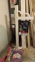 Full view of the white wooden flagstand with several holiday flags displayed and stacked at base.
