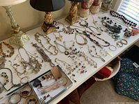 Overview photo of statement necklaces, various bracelets, earrings, and other jewelry items arranged on a table.