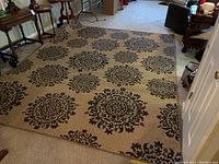 Full view of tan woven rug with dark brown medallion patterns spread on carpeted floor in living room.