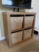 Front view of the wood cube shelf/bookcase with 4 beige fabric baskets inside each cube compartment.